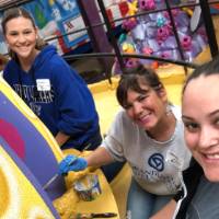 Three women painting a parade float